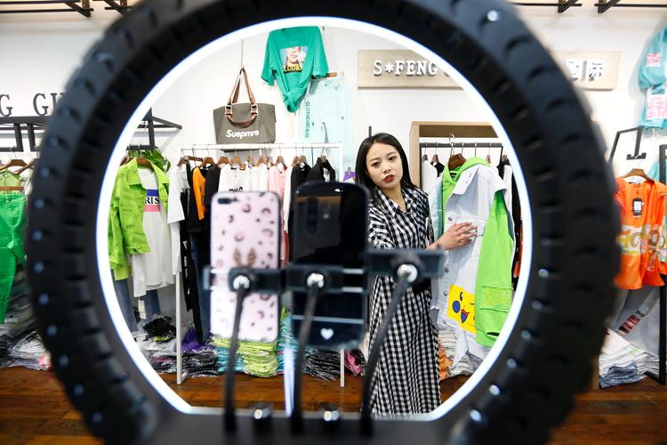 4月27日,在青岛市即墨服装批发市场,服饰销售员通过直播平台向顾客